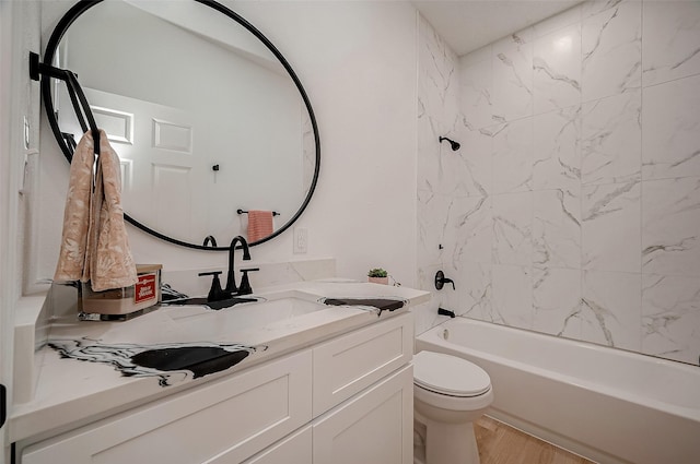 full bathroom featuring tiled shower / bath, hardwood / wood-style floors, vanity, and toilet