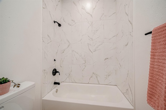 bathroom featuring tiled shower / bath combo and toilet