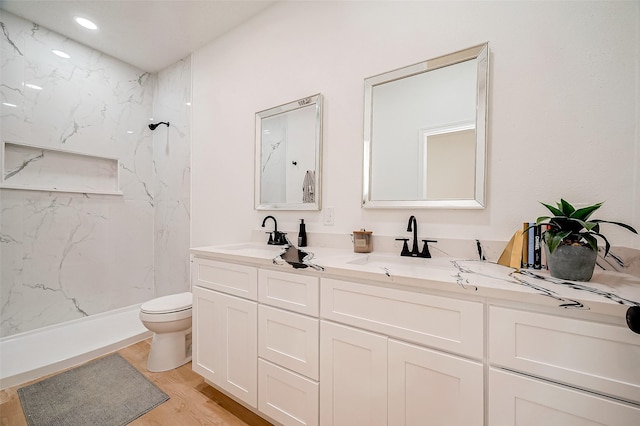 bathroom featuring vanity, wood-type flooring, toilet, and tiled shower