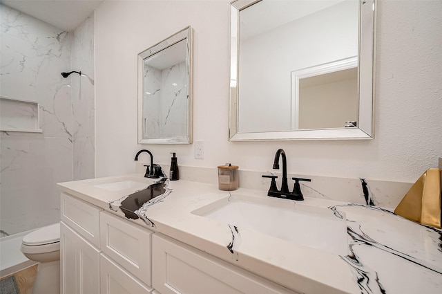 bathroom with vanity, tiled shower, and toilet