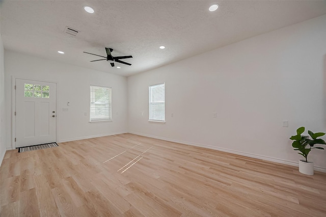 unfurnished living room with ceiling fan, a textured ceiling, and light wood-type flooring