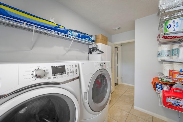 clothes washing area with light tile patterned floors and washer and dryer