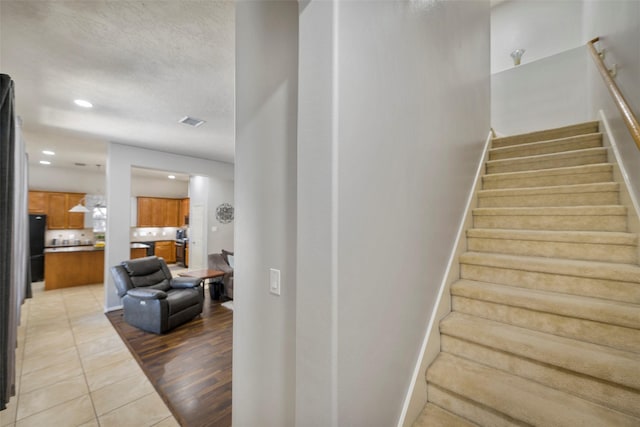 stairs featuring tile patterned floors and a textured ceiling