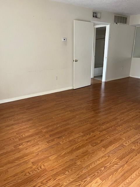 unfurnished room featuring wood-type flooring and a textured ceiling