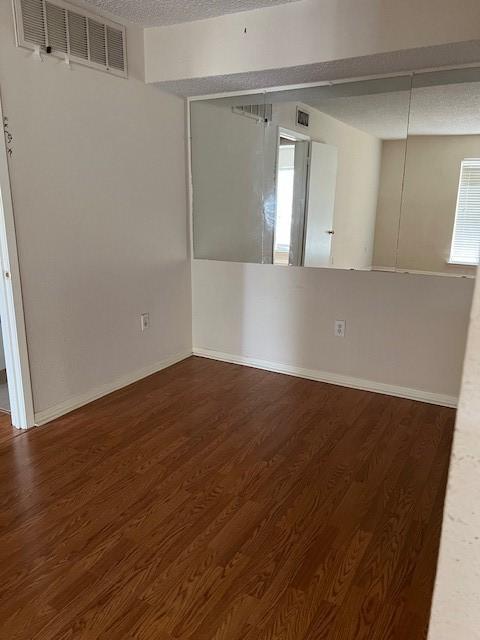 spare room with dark hardwood / wood-style floors and a textured ceiling