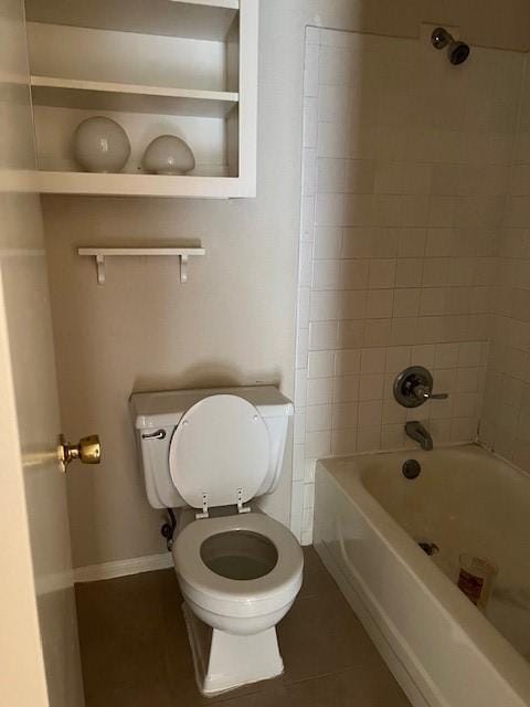 bathroom with built in features, tile patterned floors, toilet, and tiled shower / bath