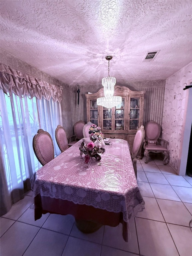 tiled dining space featuring visible vents, a chandelier, and a textured ceiling