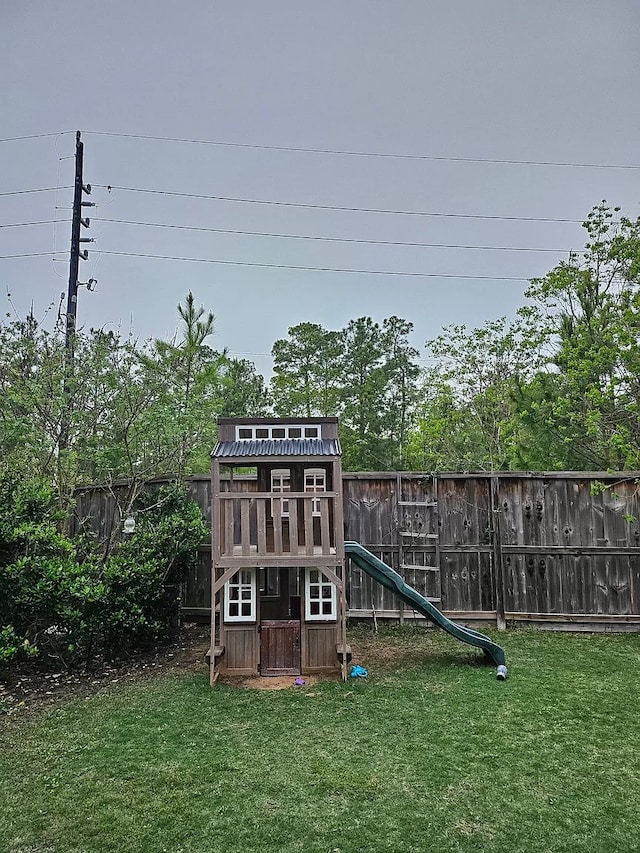 view of playground with a fenced backyard and a lawn