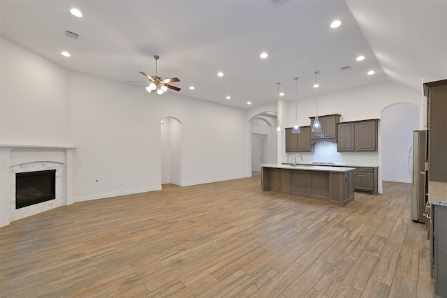 16715 Ramsay Cascades Dr, Humble, TX 77346 - kitchen with open floor plan, freestanding refrigerator, vaulted ceiling, arched walkways, and a center island with sink