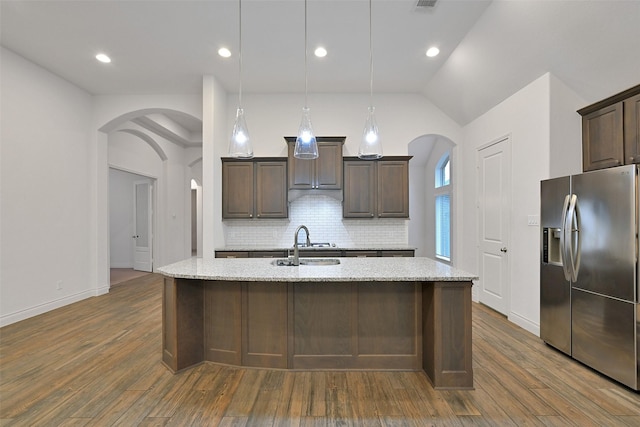 16715 Ramsay Cascades Dr, Humble, TX 77346 - kitchen featuring stainless steel fridge, arched walkways, dark brown cabinets, decorative backsplash, and lofted ceiling