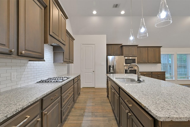 16715 Ramsay Cascades Dr, Humble, TX 77346 - kitchen with stainless steel appliances, a center island with sink, dark wood-type flooring, a sink, and light stone countertops