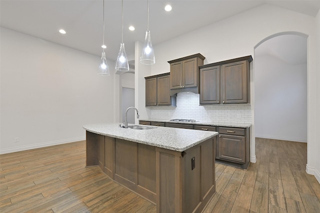 16715 Ramsay Cascades Dr, Humble, TX 77346 - kitchen with a sink, stainless steel gas stovetop, tasteful backsplash, arched walkways, and wood finished floors