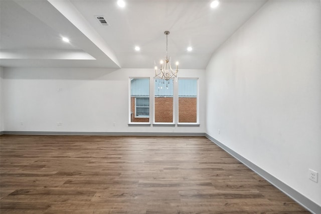 unfurnished room featuring an inviting chandelier, lofted ceiling, and dark hardwood / wood-style floors