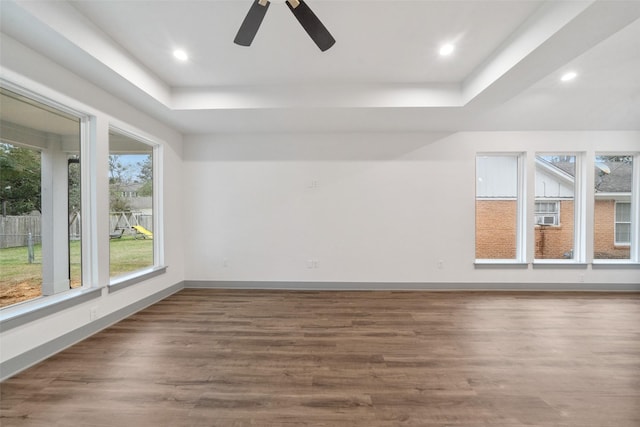 spare room with a raised ceiling, wood-type flooring, and ceiling fan