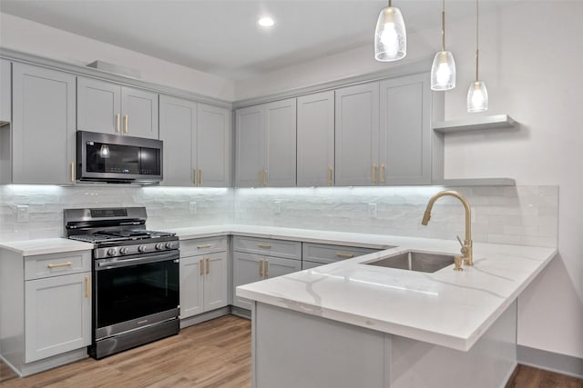 kitchen featuring sink, appliances with stainless steel finishes, gray cabinetry, hanging light fixtures, and kitchen peninsula