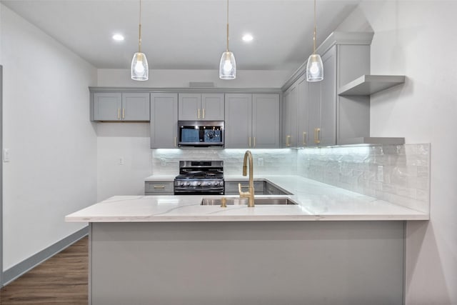 kitchen with appliances with stainless steel finishes, decorative light fixtures, sink, gray cabinetry, and light stone countertops