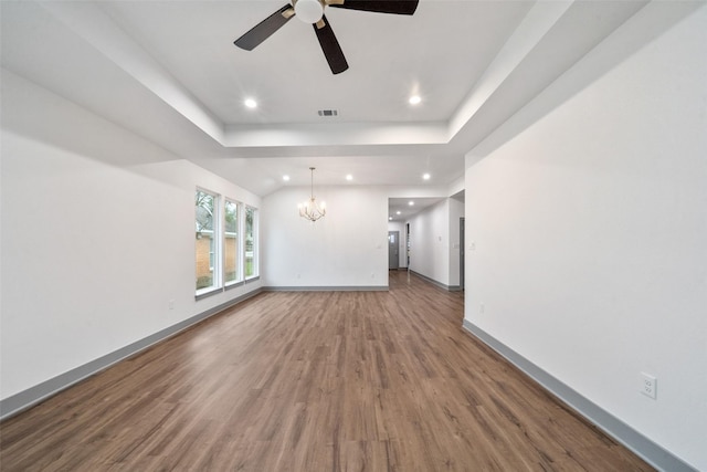 unfurnished living room with hardwood / wood-style flooring, a raised ceiling, and ceiling fan with notable chandelier