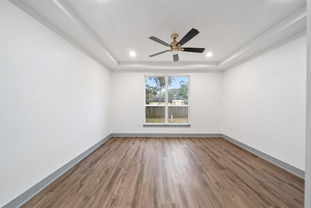 unfurnished room with a tray ceiling, wood-type flooring, and ceiling fan