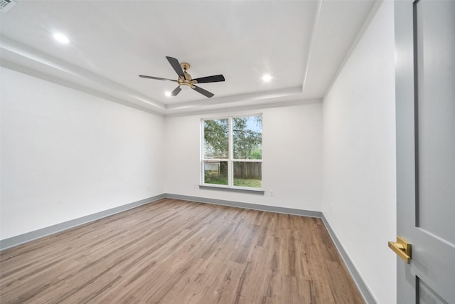 unfurnished room featuring a tray ceiling, light hardwood / wood-style flooring, and ceiling fan