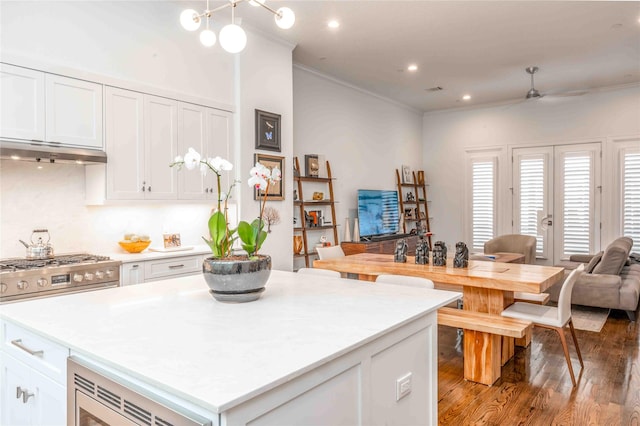 kitchen featuring hardwood / wood-style floors, white cabinetry, crown molding, and stainless steel gas range