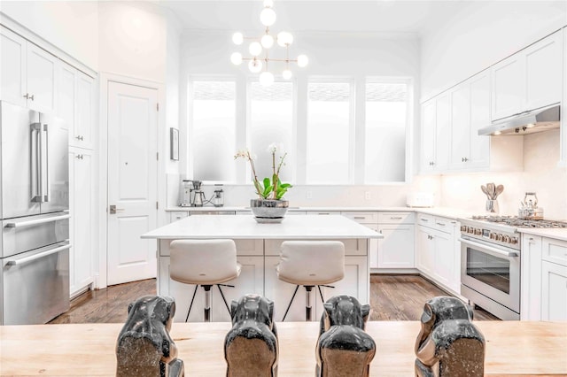 kitchen featuring high end appliances, a breakfast bar area, white cabinets, a kitchen island, and light wood-type flooring