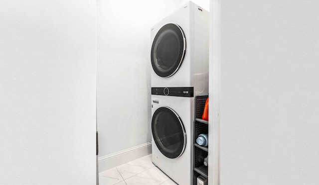 laundry room featuring light tile patterned floors and stacked washer / drying machine