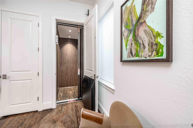 hallway with elevator and hardwood / wood-style flooring