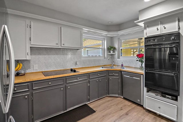 kitchen featuring gray cabinetry, sink, decorative backsplash, and black appliances