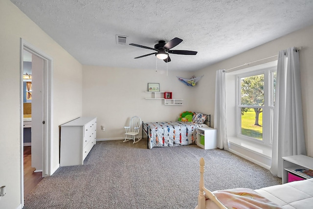 carpeted bedroom featuring ceiling fan and a textured ceiling