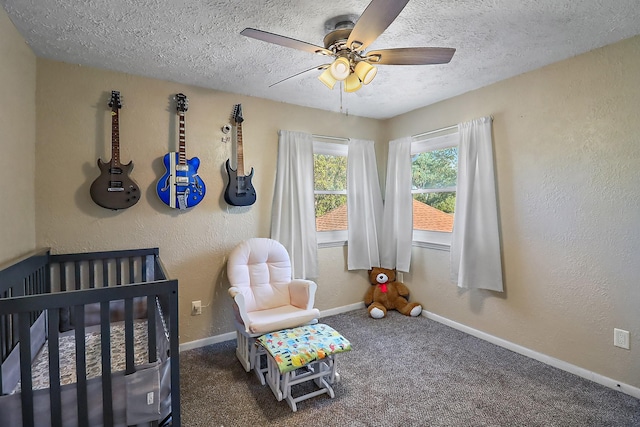 bedroom with ceiling fan, a crib, a textured ceiling, and carpet flooring