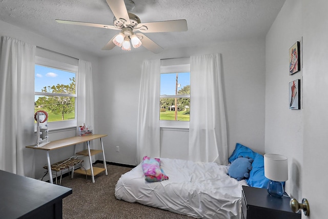 bedroom with ceiling fan, dark carpet, and a textured ceiling