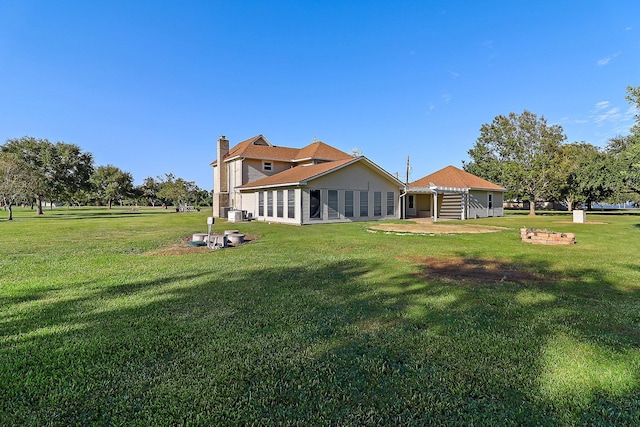 rear view of house with a yard and an outdoor fire pit