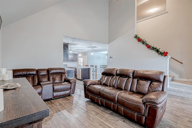 living room with sink, high vaulted ceiling, and light hardwood / wood-style flooring