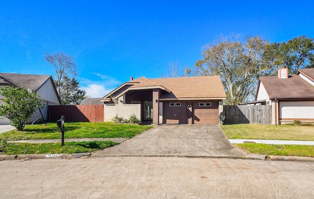 view of front facade with a front yard, fence, driveway, and an attached garage