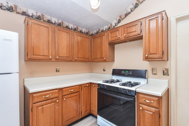 1478 Willow Wisp Dr, Missouri City, TX 77489 - kitchen with range with gas stovetop, freestanding refrigerator, light countertops, brown cabinets, and a textured ceiling