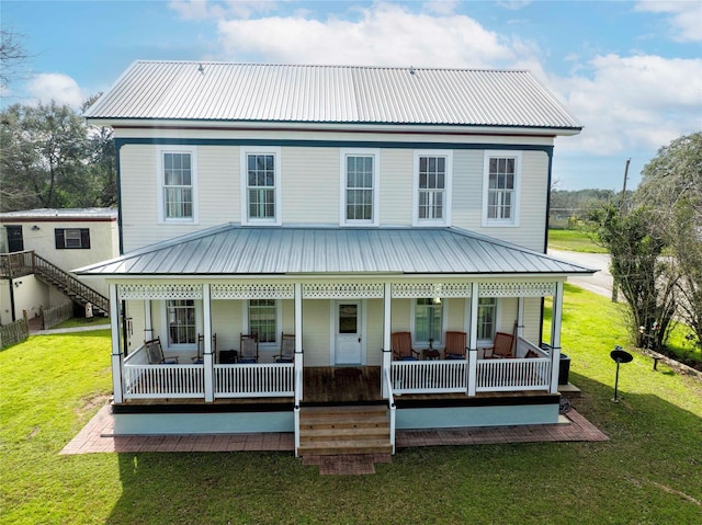 rear view of property featuring a porch, a yard, and metal roof