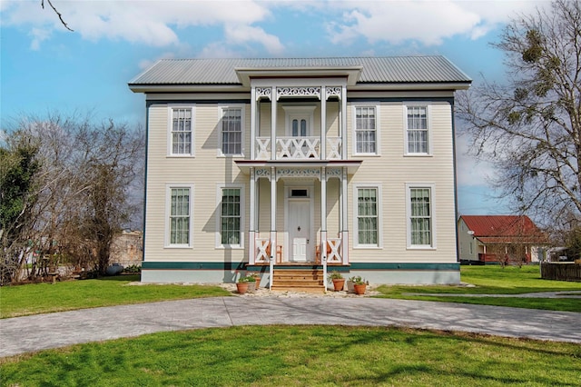 view of front of property featuring metal roof, a balcony, and a front yard