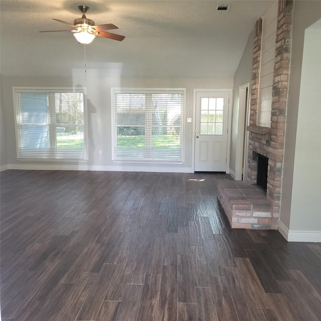 unfurnished living room with lofted ceiling, ceiling fan, dark wood-style flooring, a fireplace, and visible vents