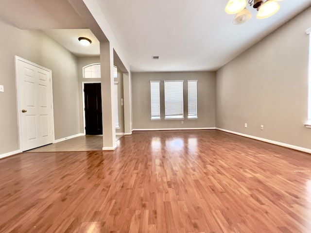 unfurnished living room with a notable chandelier and light hardwood / wood-style flooring