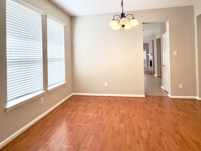 empty room featuring an inviting chandelier and hardwood / wood-style floors