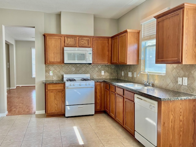 kitchen with tasteful backsplash, sink, white appliances, and light tile patterned floors