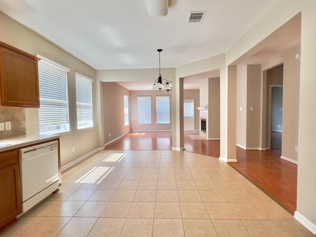 kitchen with backsplash, white dishwasher, an inviting chandelier, and light tile patterned floors