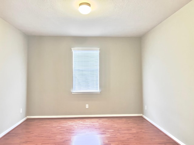 spare room featuring wood-type flooring and a textured ceiling