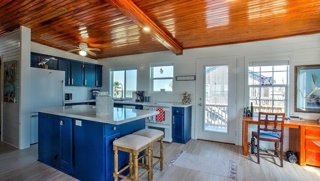 kitchen with a kitchen island, blue cabinets, sink, a kitchen breakfast bar, and light wood-type flooring