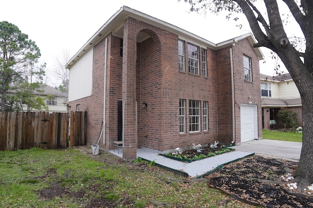 view of home's exterior with a garage, brick siding, fence, and driveway