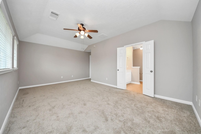 unfurnished room featuring vaulted ceiling, light carpet, a textured ceiling, and ceiling fan