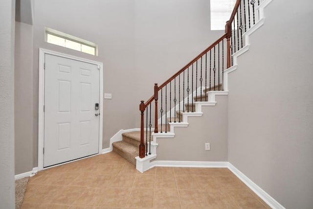 tiled foyer with a towering ceiling and a healthy amount of sunlight