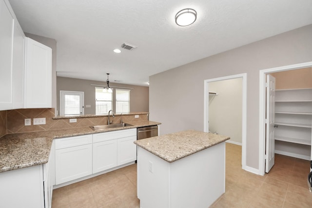 kitchen with sink, white cabinetry, tasteful backsplash, a center island, and light stone countertops