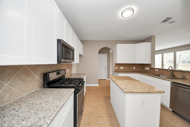 kitchen featuring appliances with stainless steel finishes, sink, white cabinets, and light stone counters