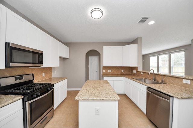 kitchen with a kitchen island, sink, white cabinets, light stone counters, and stainless steel appliances